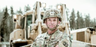 Interview: John Smith from Royal Engineers to Managing Tunnel Construction Military engineer in uniform standing confidently beside a snow-covered bulldozer.